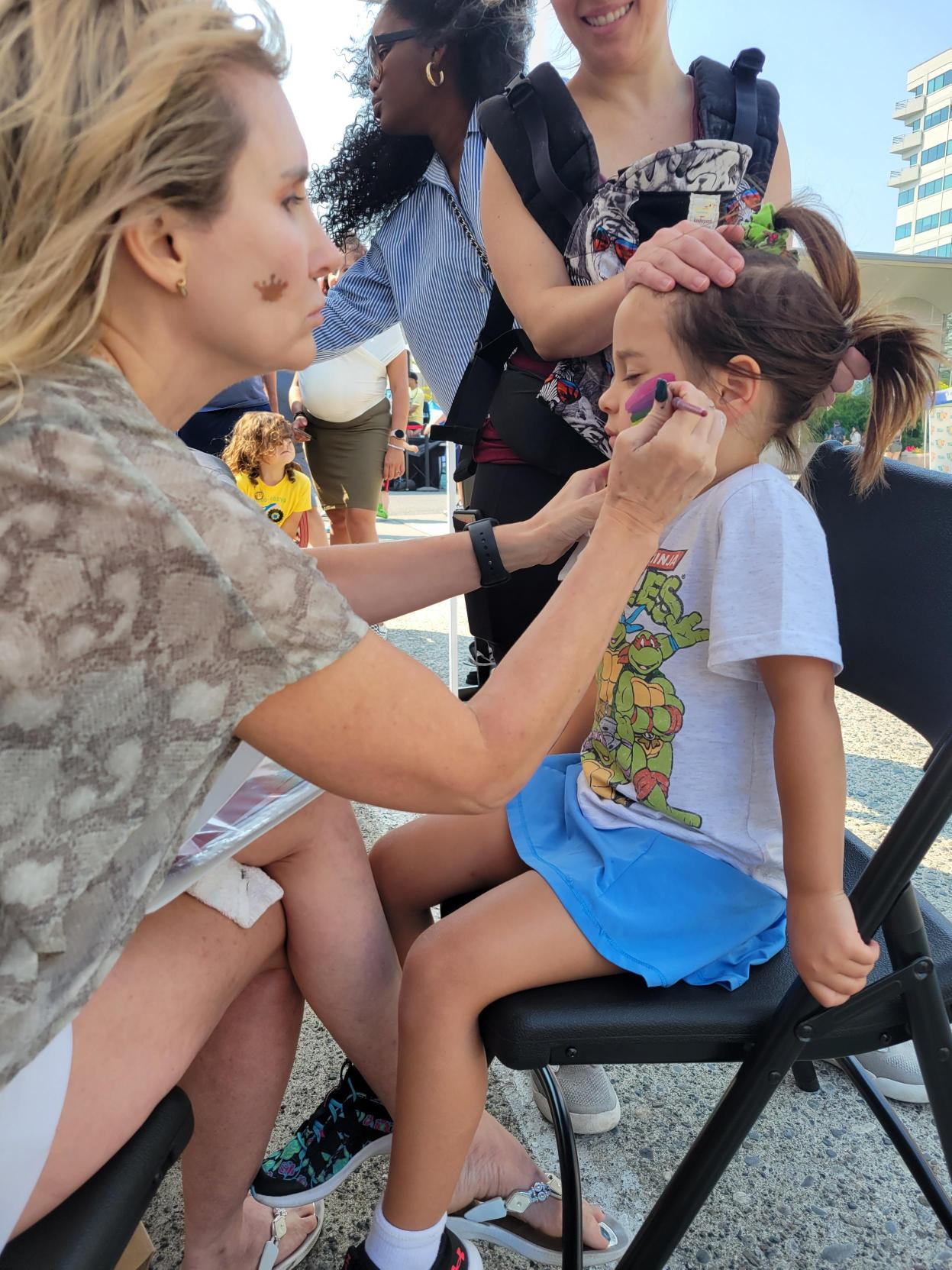 Face Painting: A volunteer paints the face of a child.